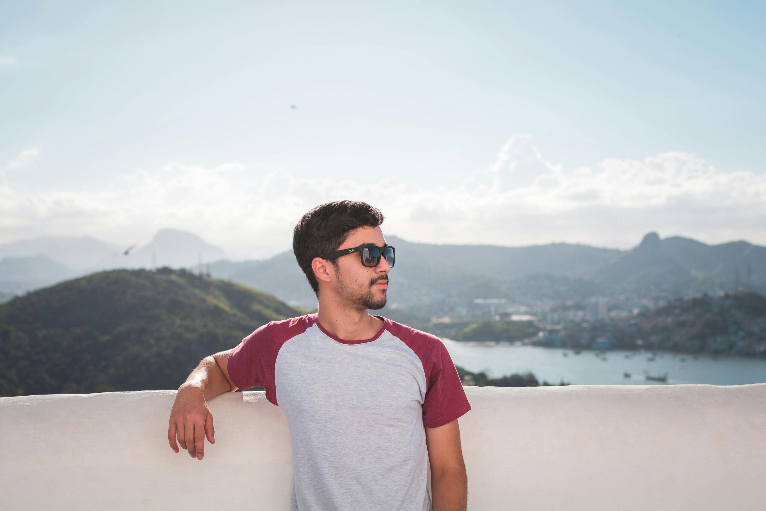 Portrait of a man in sunglasses enjoying a sunny day with a scenic mountain background.